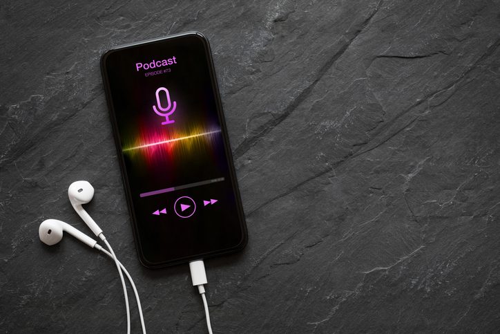 Earphones and mobile phone with podcast app on screen